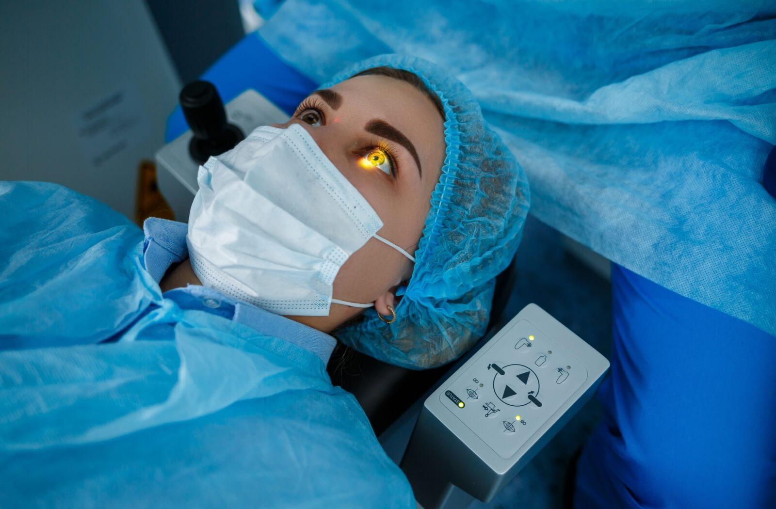 Patient undergoing LASIK eye surgery with laser focus and protective gear.